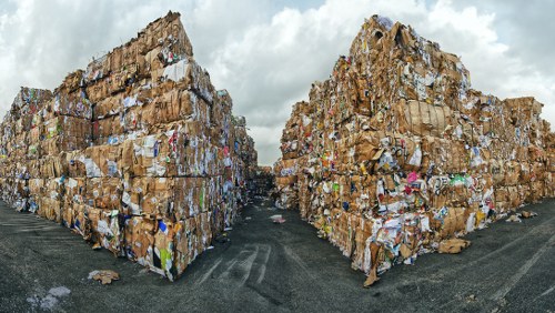 Worker wearing PPE handling waste near a skip bin